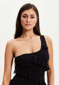 Black dress featuring a one-shoulder design with ruffled accents. The fabric has a smooth texture and a fitted silhouette.