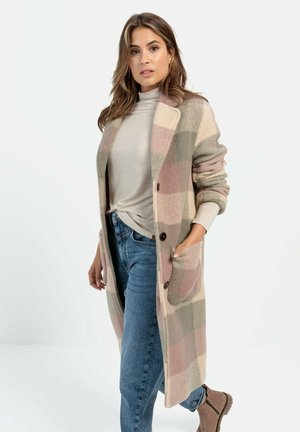 Beige and pink checkered long cardigan made of soft fabric with a collar, front pockets, and brown buttons, paired with a light top and jeans.