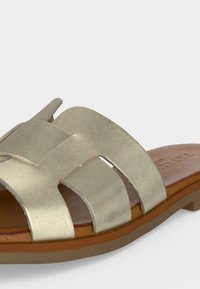 Sandale femme dorée métallisée à bout ouvert avec larges brides croisées et semelle marron rembourrée.