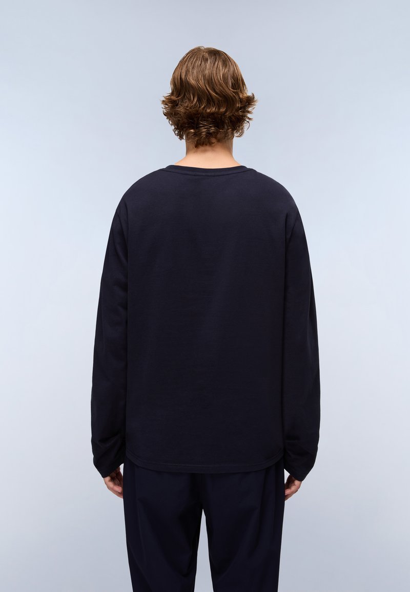 Camiseta de manga larga de color navy, hecha de material suave, presenta un cuello redondo y un ajuste holgado, con costuras visibles y un dobladillo recto.