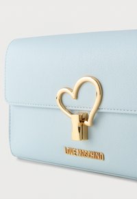 Τσάντα από γαλάζιο δέρμα με υφή, με χρυσό κούμπωμα σε σχήμα καρδιάς και πλακέτα με το όνομα της μάρκας Love Moschino.