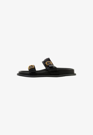 Black flat slide sandal with two adjustable straps featuring gold-tone buckles, shown in side view on white background.