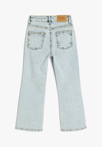 Jeans de mezclilla azul claro con pierna recta, que presentan un parche de cuero en la cintura, dos bolsillos traseros y un detalle de desgaste mínimo.