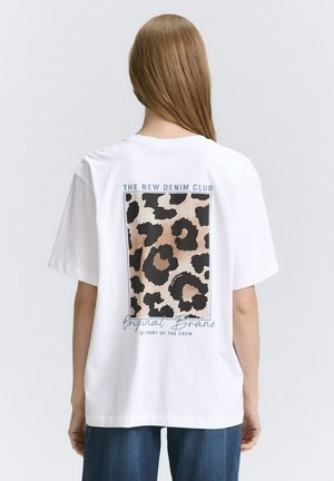 Weißes Baumwoll-T-Shirt mit einem Leopardenprint-Graphic auf dem Rücken, mit Text über und unter dem Design. Kurze Ärmel und lockere Passform.