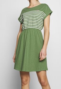 Grünes Strickkleid mit gestreiftem grün-weißem Oberteil, elastischem Bund, kurzen Ärmeln und kleiner Herzstickerei auf der Brust.