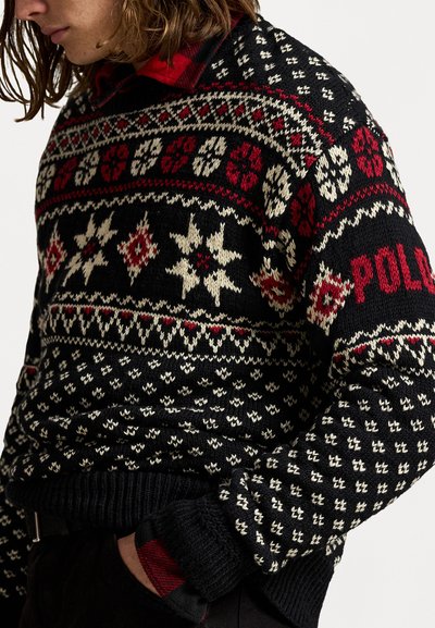Melna adīta džemperis ar sarkaniem un baltajiem Fair Isle rakstiem, kas ietver sniegpārsliņas un dimantus. Ribotās aproces un apakšmala, zīmols "POLO" sarkanā krāsā.
