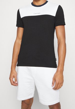 Black and white short-sleeve t-shirt with a crew neck by Calvin Klein, featuring contrasting color block design and soft cotton material.