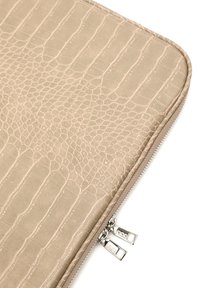 Beige laptop sleeve med krokodilleprægning, der har en glat overflade og sølvfarvet dobbelt lynlås. Rektangulær form med rene kanter.