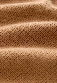 Braun gestrickter Stoff mit einem strukturierten Muster, das diagonale Linien und sichtbare Fasern aufweist, was ein weiches, warmes Aussehen erzeugt.