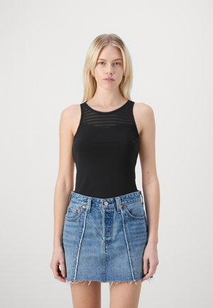 Top negru fără mâneci, cu un design transparent în dungi la bust, asortat cu o fustă mini din denim albastru deschis, cu margini desfăcute și buzunare frontale.