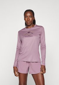 Long-sleeve athletic top and shorts in lavender fabric, featuring a printed mountain logo in darker purple on the chest. Smooth texture.