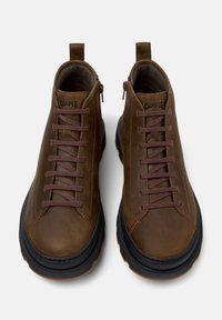 Brown leather ankle boots with a rounded toe, brown laces, and a black rubber sole. Features a low top and a loop at the heel for easy wear.