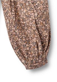 Braun-blütiges Muster auf Stoff mit gerafftem Bund. Kleine rosa, weiße und gelbe Blumen auf dunklem Hintergrund. Leicht und strukturiert.