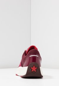 Burgundowe buty sportowe z górą z siateczki i lakierowanej skóry, biała podeszwa środkowa i teksturowana brązowa podeszwa zewnętrzna z akcentem w postaci czerwonej gwiazdy.