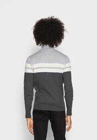 Maglione a collo alto a righe grigie e grigio scuro con maniche lunghe, polsi e orlo a coste, texture liscia, design minimalista.