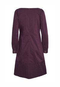 Violetti puuvillamekko pitkillä hihoilla, poimutetulla helman ja hillityillä puffiolkapäillä. Kultaiset nappikoristeet hihansuissa. Takana vetoketjukiinnitys.