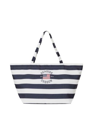 Sac fourre-tout rayé bleu marine et blanc avec poignées, avec le texte « Seaside Oregon » et un petit drapeau américain avec des coordonnées au centre devant.
