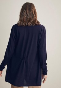 Langarm-Hemden mit lässiger Passform aus dunkelblauem Stoff. Mit einer gerafften Detail am Rücken und einem abgerundeten Saum ausgestattet. Weiche und leichte Textur.