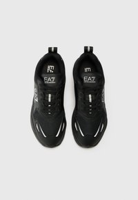 Zwarte sportschoenen met een mesh bovenkant, getextureerde accenten en reflecterende details. Heeft een vetersluiting en een gevoerde kraag.