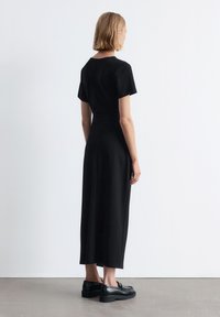 Schwarzes, kurzärmeliges Kleid mit taillierter Passform, das bis zur Mitte der Wade reicht, und einer geraden Silhouette. Verfügt über glattes Material und ein minimalistisches Design.