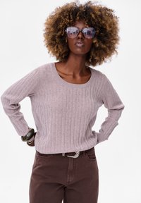 Lichtpaars geribbeld trui met een ronde hals en lange mouwen, gecombineerd met een bruine broek en een decoratieve riemgesp.