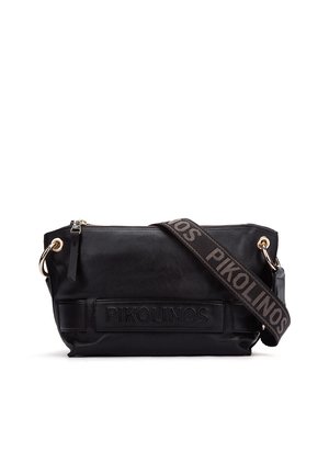 Bolso bandolera de cuero negro con una correa ancha de tela que lleva el texto "PIKOLINOS" y cierre superior con cremallera.