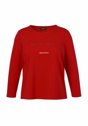 Rotes Langarm-T-Shirt aus weichem Stoff mit geprägtem Text "WÄHLE FREUDE" und "MACHE DEN TAG GRANDIOS" in kontrastierenden Farben.