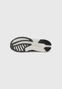 Sko såle i svart og hvitt gummi, med et teksturert design med spor og mønstre for trekkraft og grep, flat form, og ingen synlig merkevare.