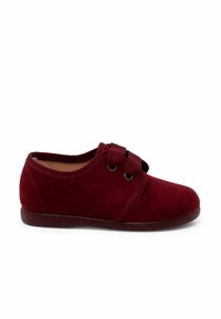 Scarpa in suede rossa con punta arrotondata, chiusura con fascetta elastica e suola piatta. Texture liscia con design semplice e dettagli di cucitura.