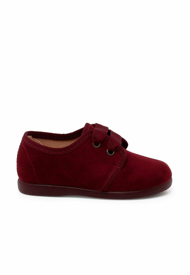 Scarpa in suede rossa con punta arrotondata, chiusura con fascetta elastica e suola piatta. Texture liscia con design semplice e dettagli di cucitura.