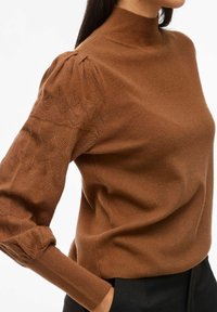 Pull en laine marron à col roulé avec un corps ajusté et des manches bouffantes texturées comportant des motifs géométriques. Texture lisse et douce dans l'ensemble.
