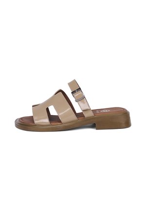 Beige Open-Toe-Sandale mit Blockabsatz, breiten Riemen mit Ausschnitten und verstellbarem Knöchelriemen auf weißem Hintergrund.