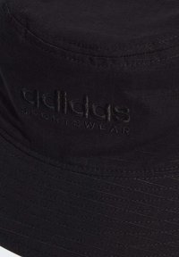 Cappello a secchiello nero realizzato in tessuto testurizzato con logo adidas in rilievo e dettagli di cucitura orizzontale.