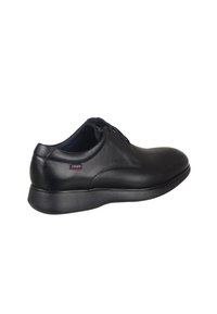 Zapato de cuero negro con un acabado suave, suela resistente y cordones. Presenta un pequeño logotipo rojo en el lateral, ofreciendo un diseño casual pero refinado.