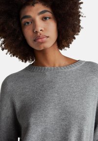 Szary dziergany sweter z szerokim, prążkowanym dekoltem i miękką fakturą. Ma luźny krój, długie rękawy i lekką konstrukcję.