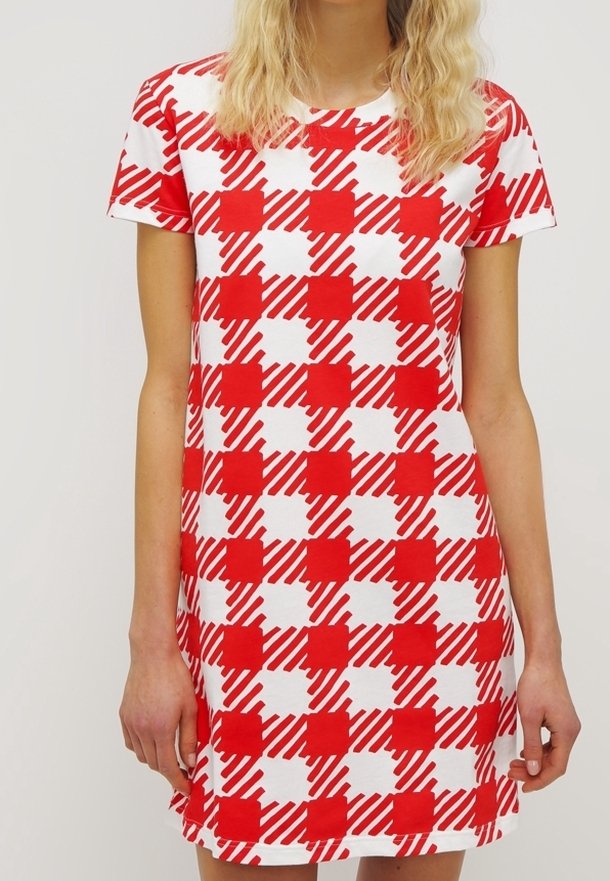 Femme portant une robe à manches courtes avec un motif à carreaux rouge et blanc comprenant des carrés unis et à rayures diagonales.