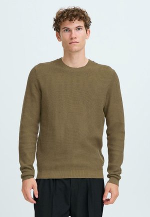 Olijfgroene gebreide trui met een ronde hals, lange mouwen en een ribbelstructuur. Heeft een aansluitende zoom en boorden.