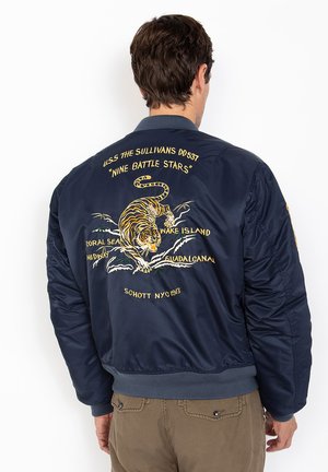 Donkerblauwe bomberjack van satijnachtige stof, met een geborduurde oranje tijger en militaire tekst op de rug, geribbelde manchetten en tailleband.