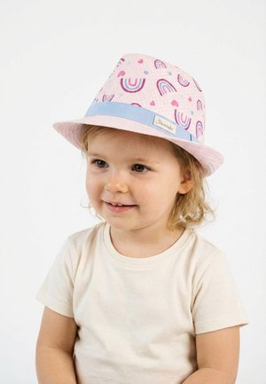 Toddler wearing a light pink fedora hat with rainbows and heart patterns and a blue band, smiling and looking slightly to the side.