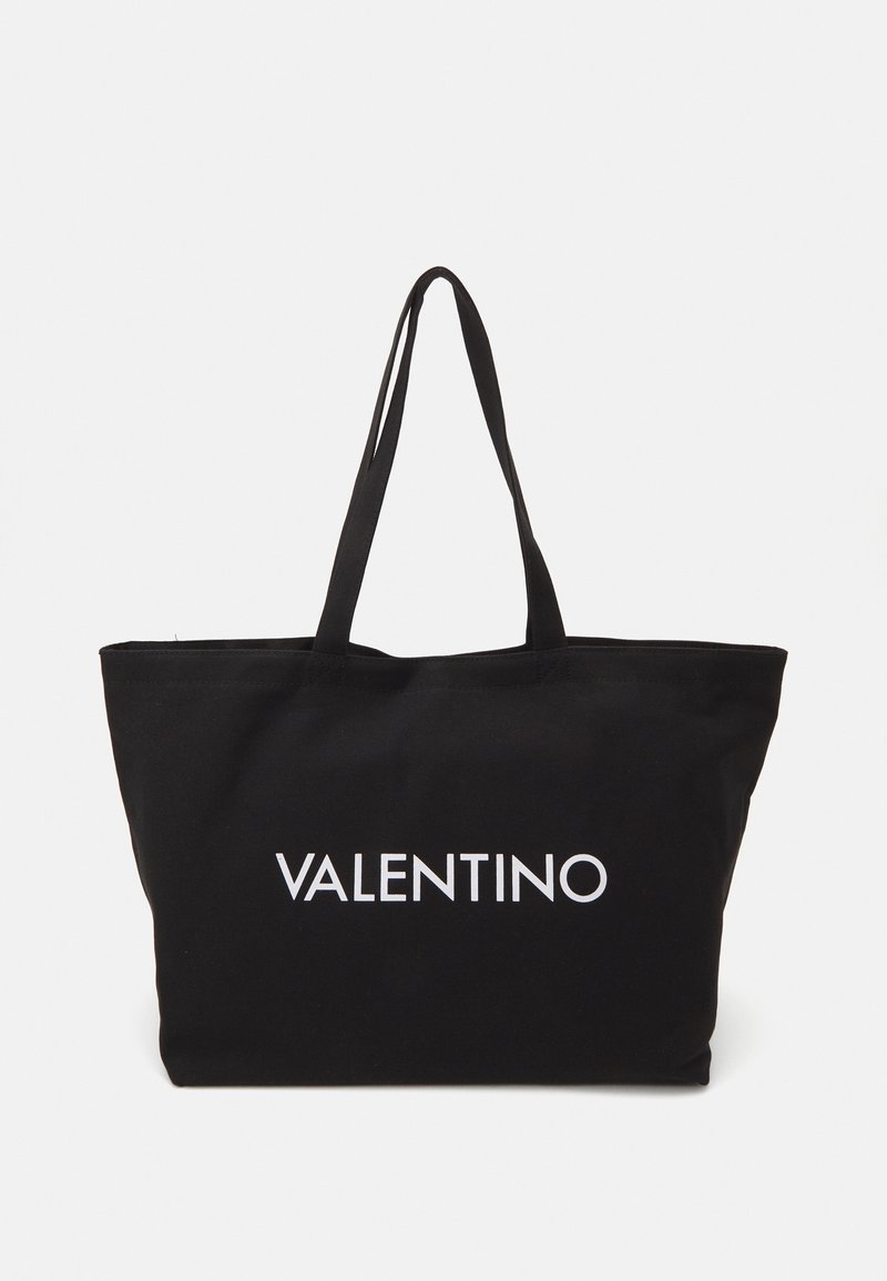 Black tote bag made of fabric, featuring two sturdy handles and white "VALENTINO" text printed prominently on the front.