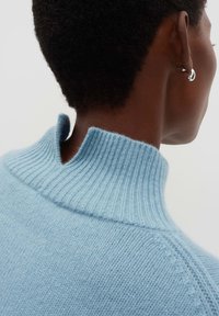 Maglione a costo leggero blu chiaro con colletto alto, caratterizzato da un'apertura sul retro del collo. Tessuto morbido e dettagli di design senza cuciture.