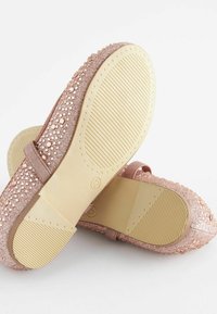 Zapatos color oro rosado con un upper texturizado que incorpora rhinestones y una suela lisa y reforzada con ranuras paralelas para mayor tracción.