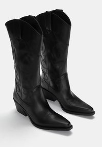 Zwarte leren cowboylaarzen met spitse neuzen, lage gestapelde hakken en decoratieve stikpatronen langs de zijkanten.