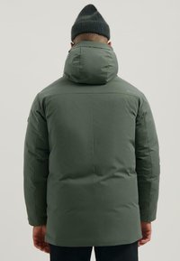 Groene pufferjas met een hoge kraag en afneembare capuchon. Beschikt over een gladde, gewatteerde textuur en subtiele logo-opschrift op de achterkant.