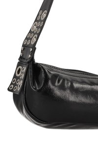 Sort taske i imiteret læder med en let buet form, forsynet med sølvfarvede, runde nitter på remmen og en lynlåsforsegling øverst.