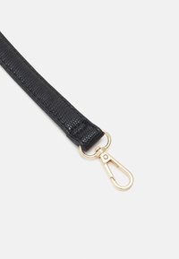 Sangle noire texturée avec un fermoir pivotant en métal doré, présentée sur un fond uni clair.