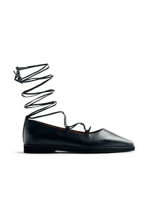 Ballerines en cuir noir avec un embout pointu et une bride à spirale noire à la cheville. Caractérisées par une texture lisse et une semelle basse pour plus de confort.