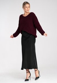 Bordowy, puszysty sweter w parze z czarną satynową sukienką na ramiączkach i czarnymi szpilkami; krótki, oversize'owy krój z prążkowanymi mankietami.