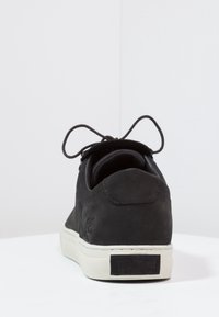 Baskets en daim noir avec un bout arrondi, des lacets et une semelle en caoutchouc blanche. Présentent un patch logo au talon et des coutures contrastantes.