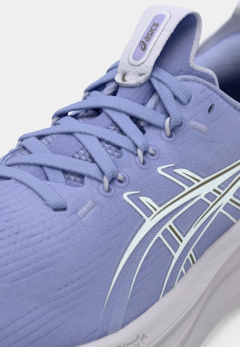 Chaussure de sport violet clair avec un tissu texturé, des lacets et un embout renforcé. Présente un logo blanc et des rayures décoratives sur le côté.